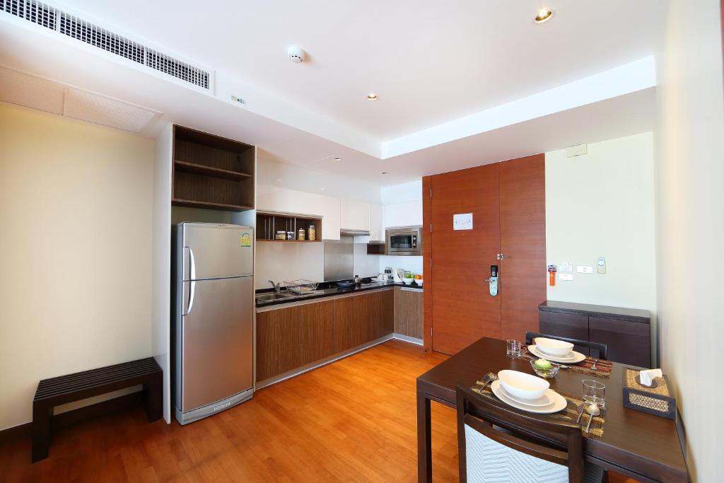 An open-plan residence kitchen with a full-height refrigerator and adjoining dining table.