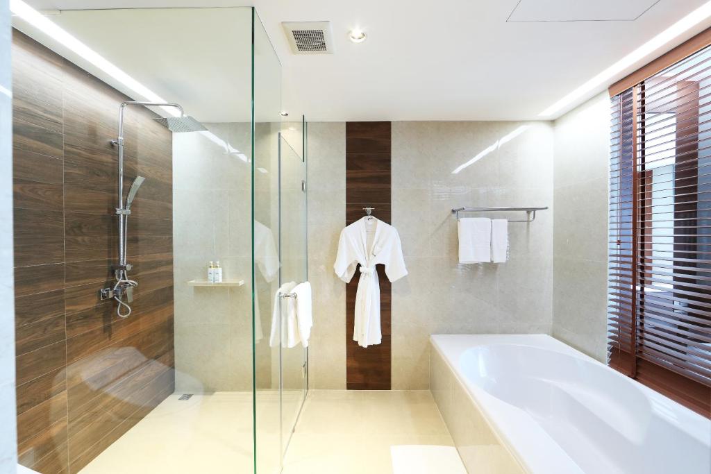 A spacious bathroom pairing a glass shower with a large tub beside wooden blinds.