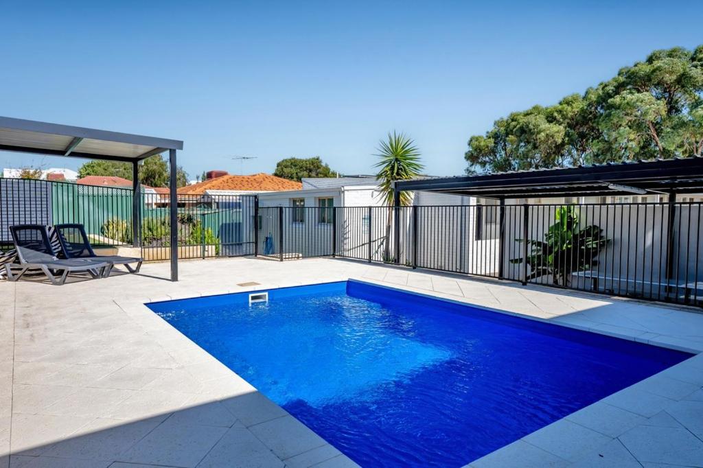 a blue swimming pool in a yard with a fence at Palm Beach Villas by Rockingham Apartments in Rockingham