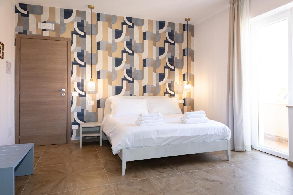 a bedroom with a white bed and a wall with a pattern at Guest house - L'amante e il marinaio in Fiumicino