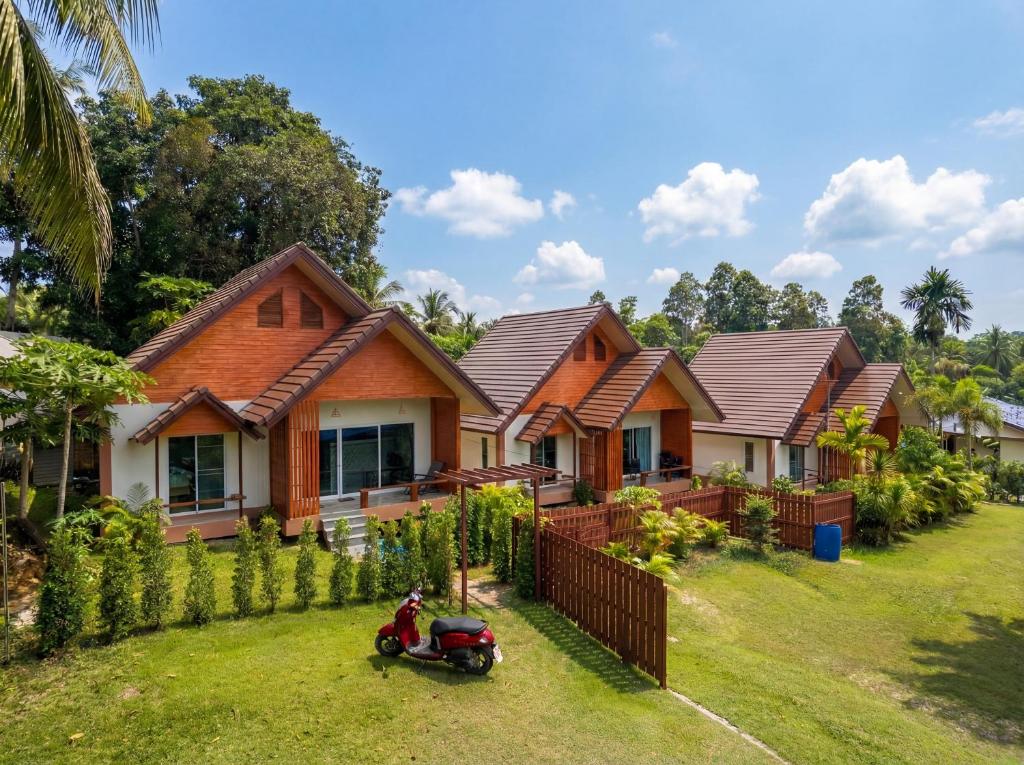 a row of houses with a scooter parked in the yard at The Triangle Villas in Srithanu