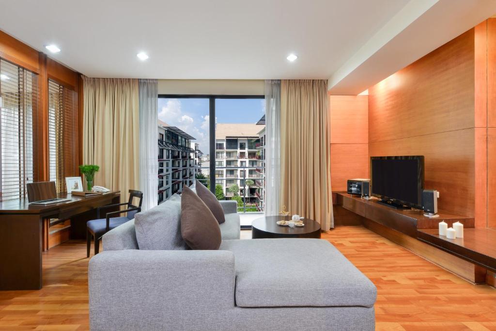 A spacious living room with a sectional sofa, desk, television and large window.