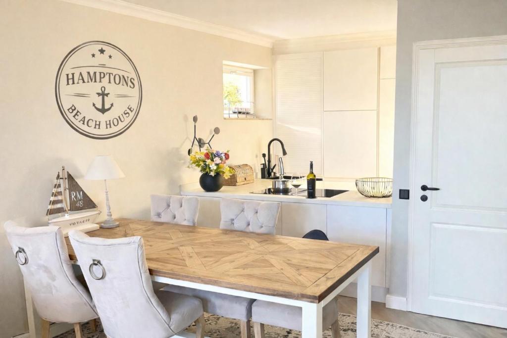 a kitchen with a wooden table and a sink at Hamptons Beach House Grömitz inklusive Saisonstrandkorb in Grömitz