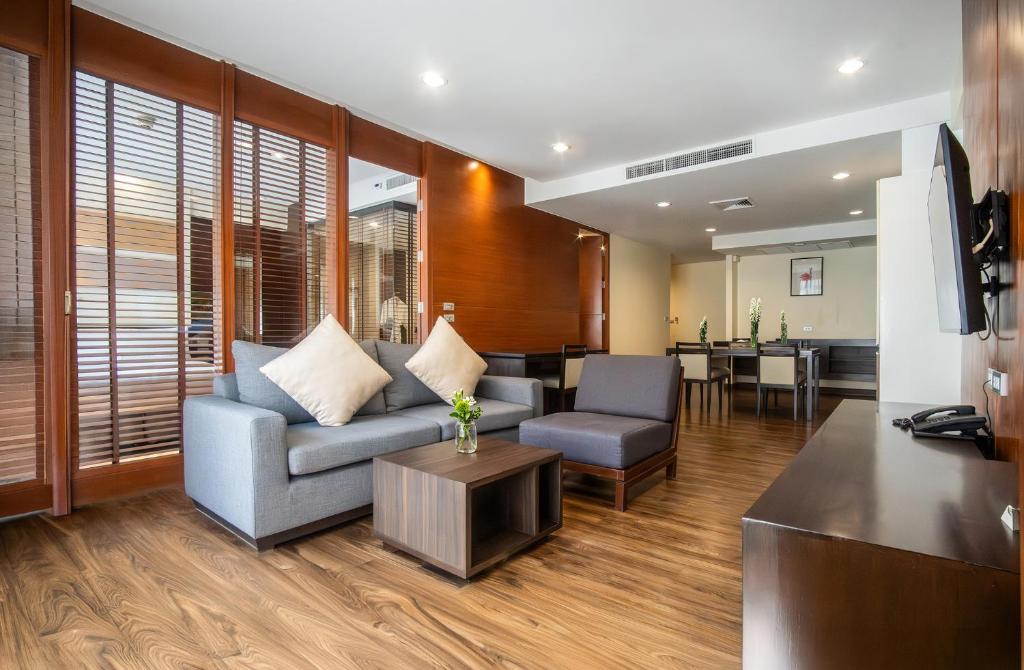 A living room with a sofa, armchair, television and adjoining dining area.