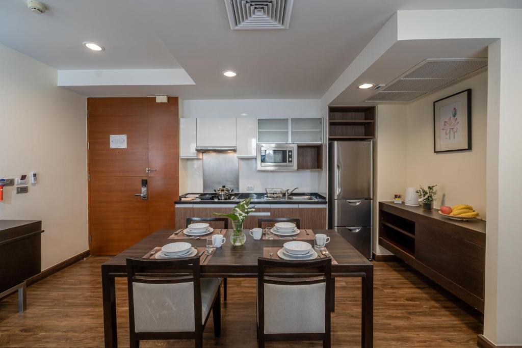 A four-seat dining table facing a compact apartment kitchen.