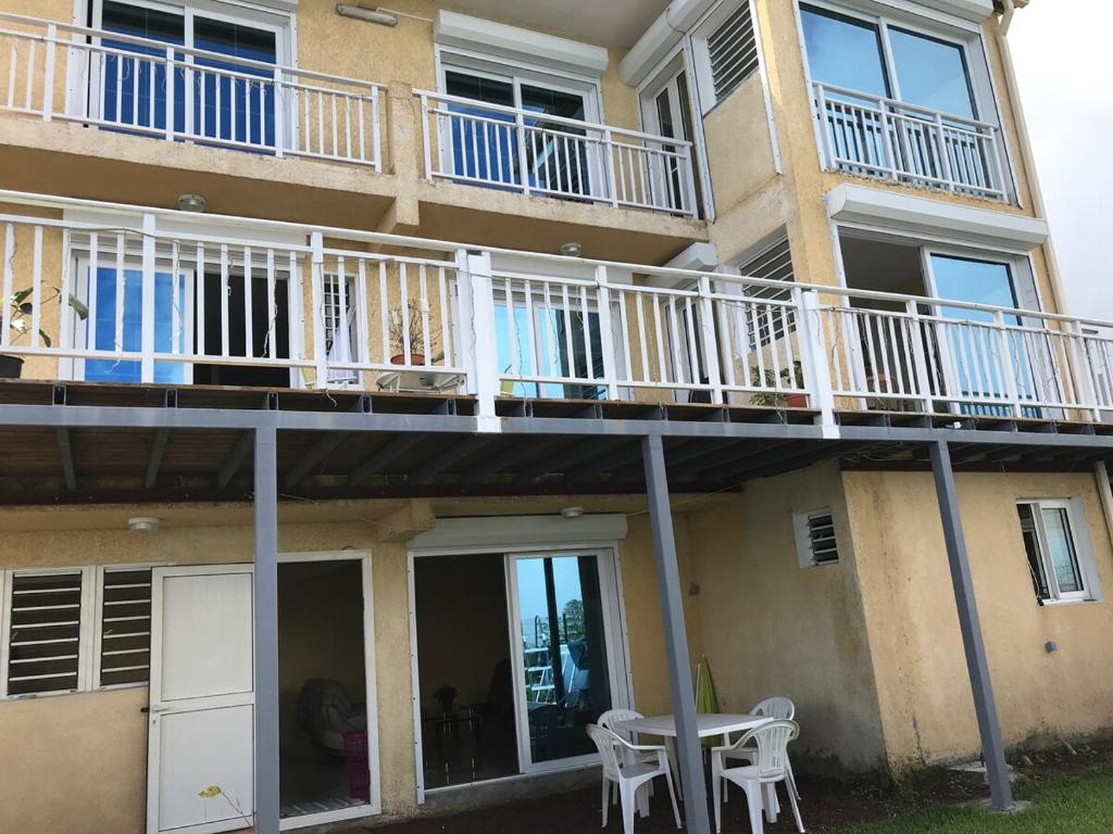 a building with a balcony with a table and chairs at Kaz Toutoune in Saint-Leu