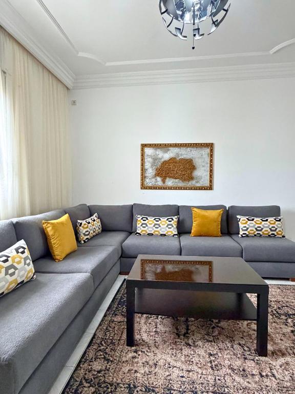 a living room with a blue couch with yellow pillows at 2 chambres tout confort - calme absolue in Temara