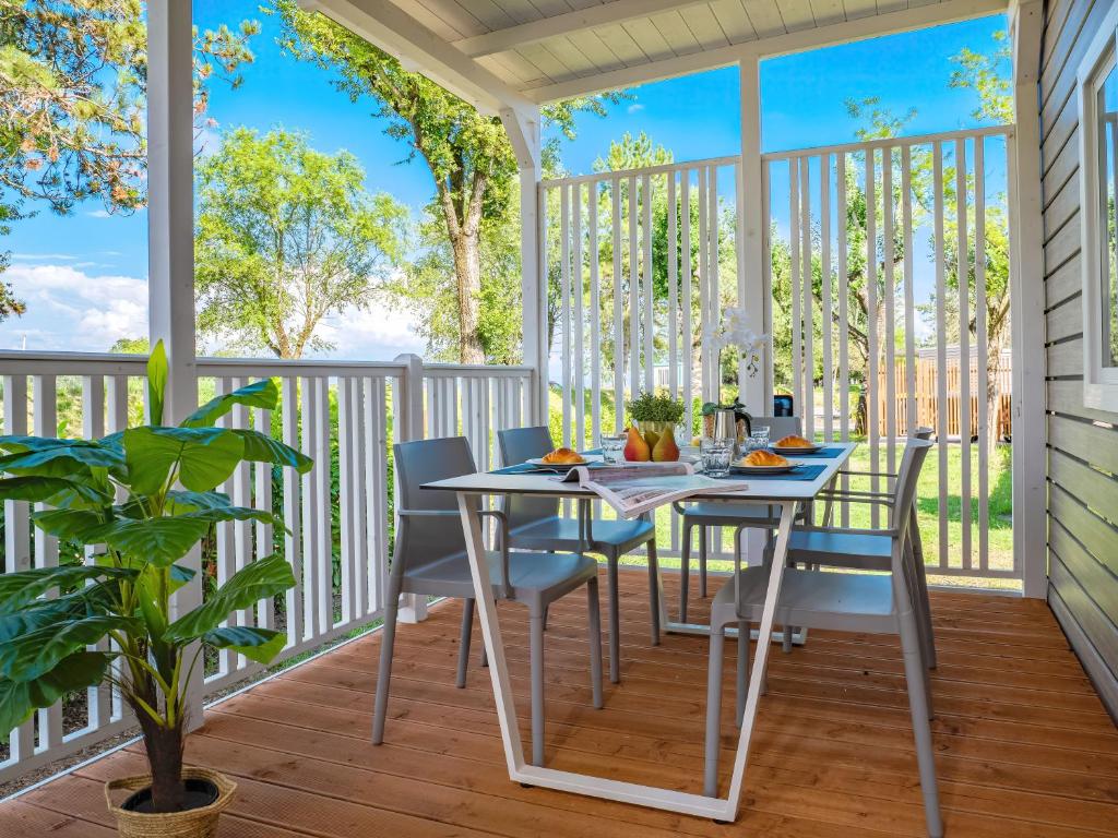 eine überdachte Veranda mit Tisch und Stühlen in der Unterkunft Hotiday Lodge Grado in Grado