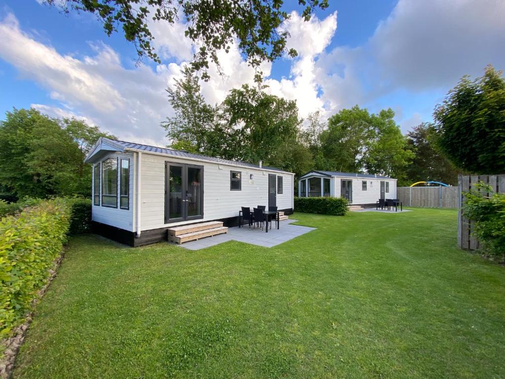 a small white cabin in a yard with a lawn at Chalet op Camping Mounewetter in Witmarsum