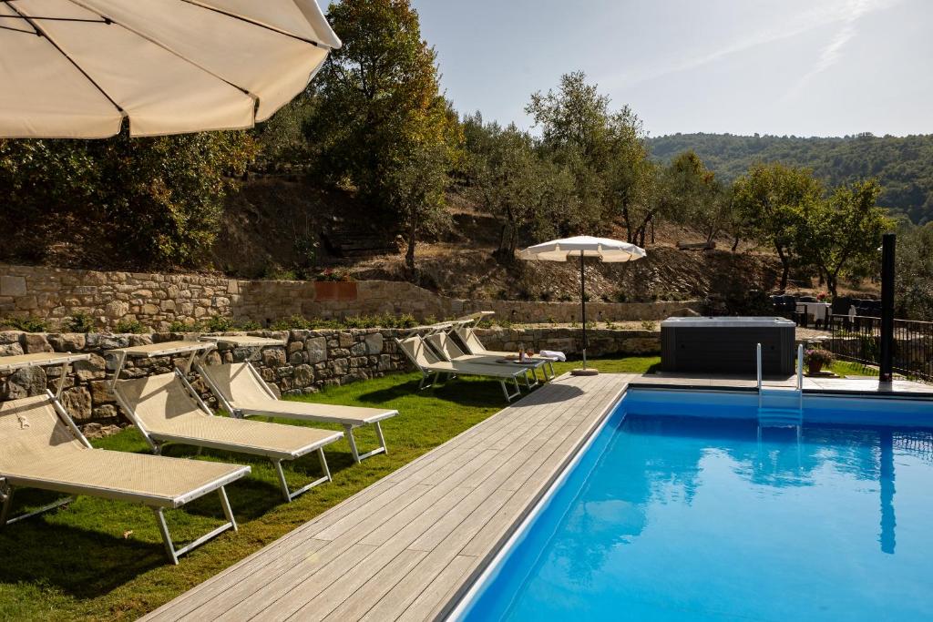 a swimming pool with lounge chairs and an umbrella at Agriturismo Santo Stefano in Polvano