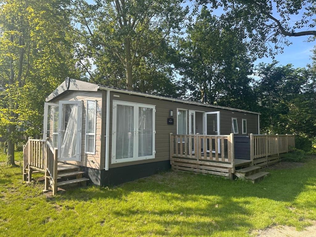 a small cabin with two decks in the grass at Chalet am Wattenmeer Holland in Lauwersoog