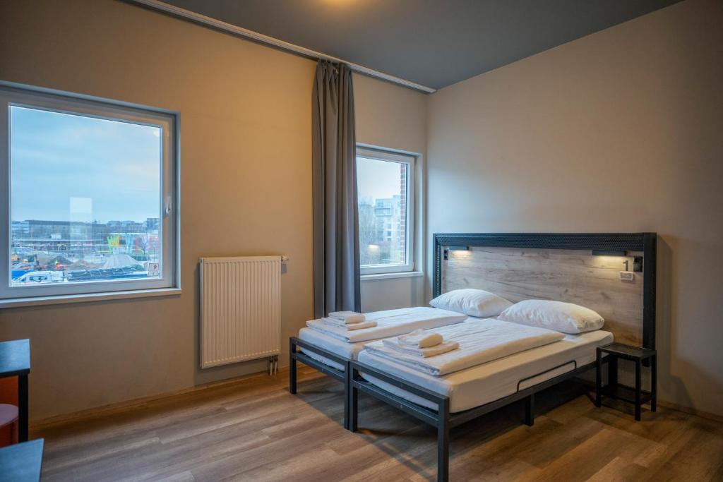 a bedroom with two beds and two large windows at a&o Copenhagen Nørrebro in Copenhagen