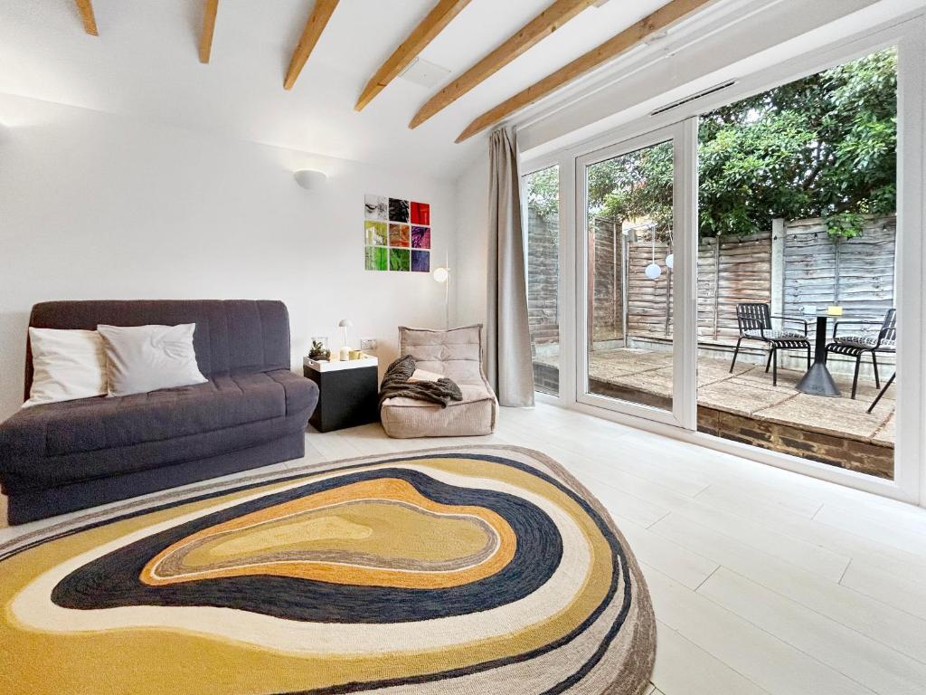 a living room with a couch and a large window at Modern self contained tiny home with patio in Loughton