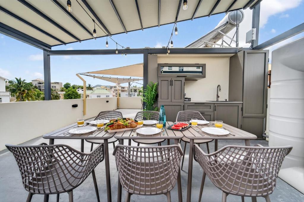 a patio with a table and chairs on a balcony at Rooftop & Jacuzzi privé à 5 min de la plage in Flic-en-Flac