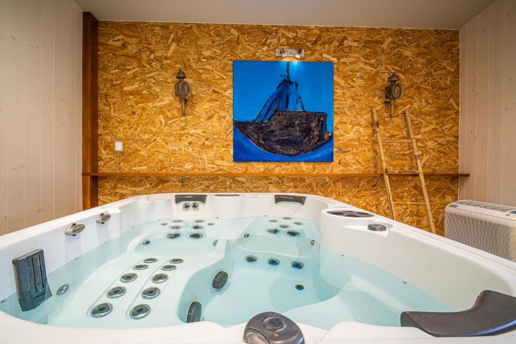 a bath tub in a room with a picture of a ship at Au nid d'Alsace - SPA et sauna privé in Orschwiller