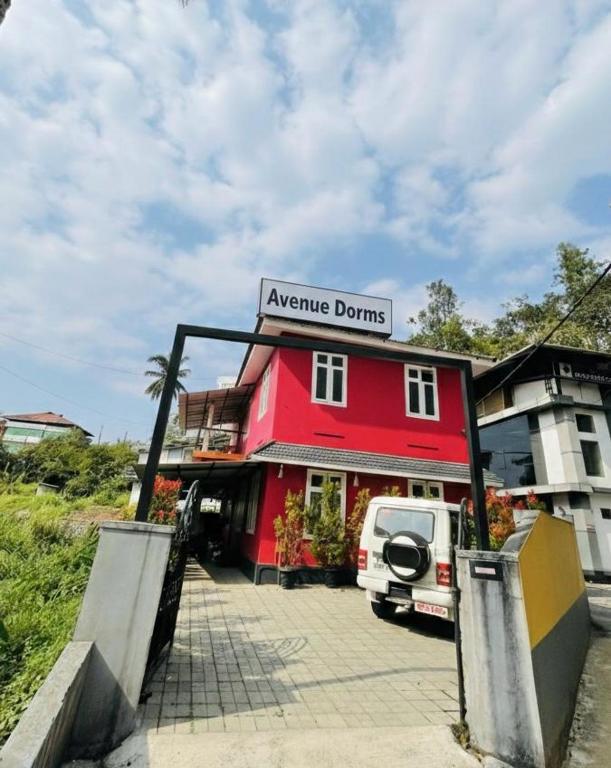 a red building with a van parked in front of it at Avenue Dorms in Kalpetta