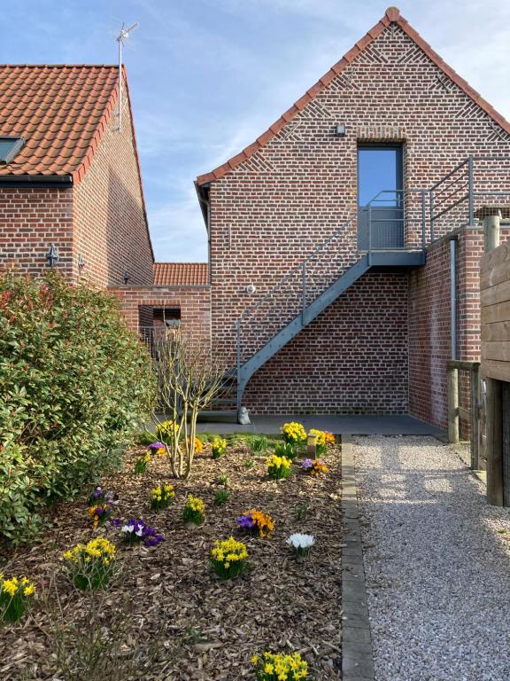 a garden in front of a brick building with flowers at Le Gîte des Fèves in Lecelles