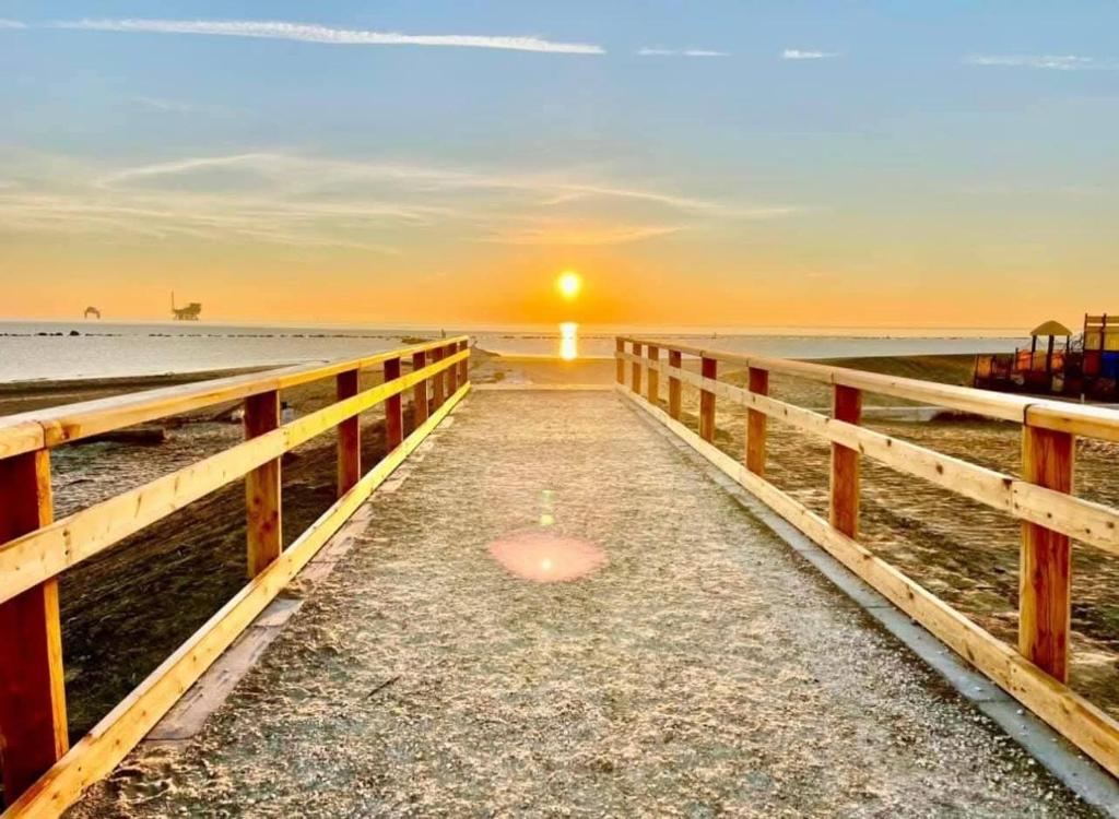 a pier on the beach with the sunset in the background at La Dolce 1 in Lido di Dante