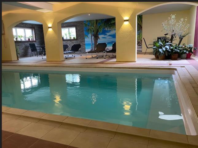 a swimming pool in a house with chairs and tables at HotelPension Weberhof in Ebersberg