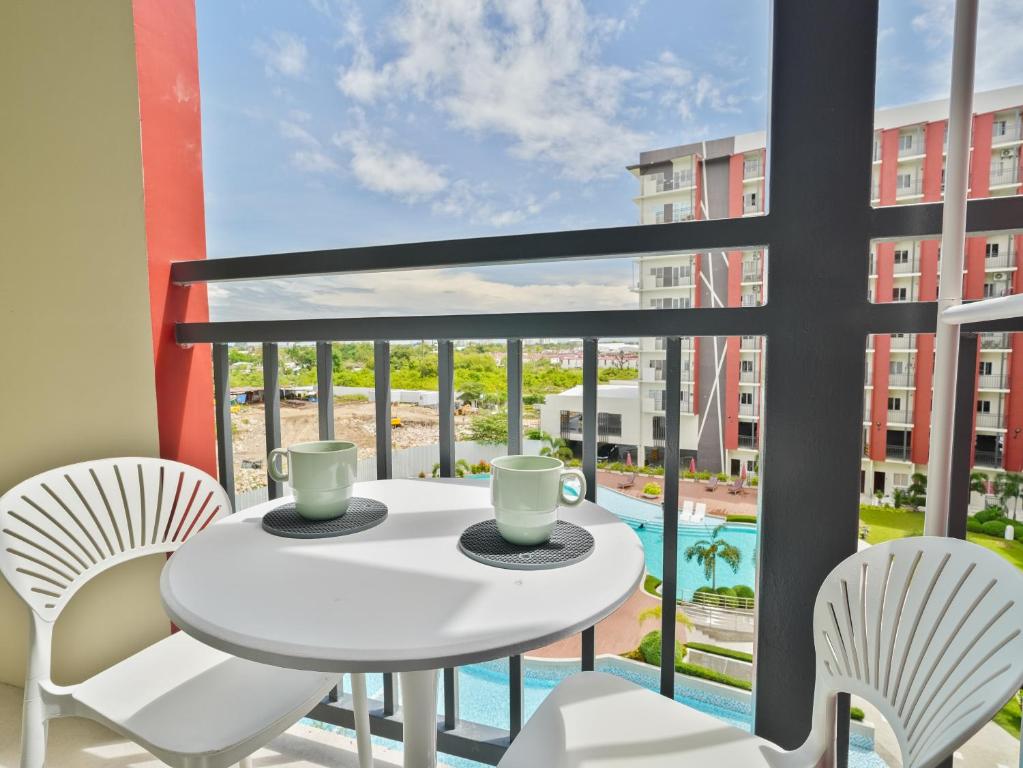 a balcony with a white table and chairs and a pool at Kajas Condo Luxe at Primeworld District near Mactan-Cebu International Airport in Lapu Lapu City