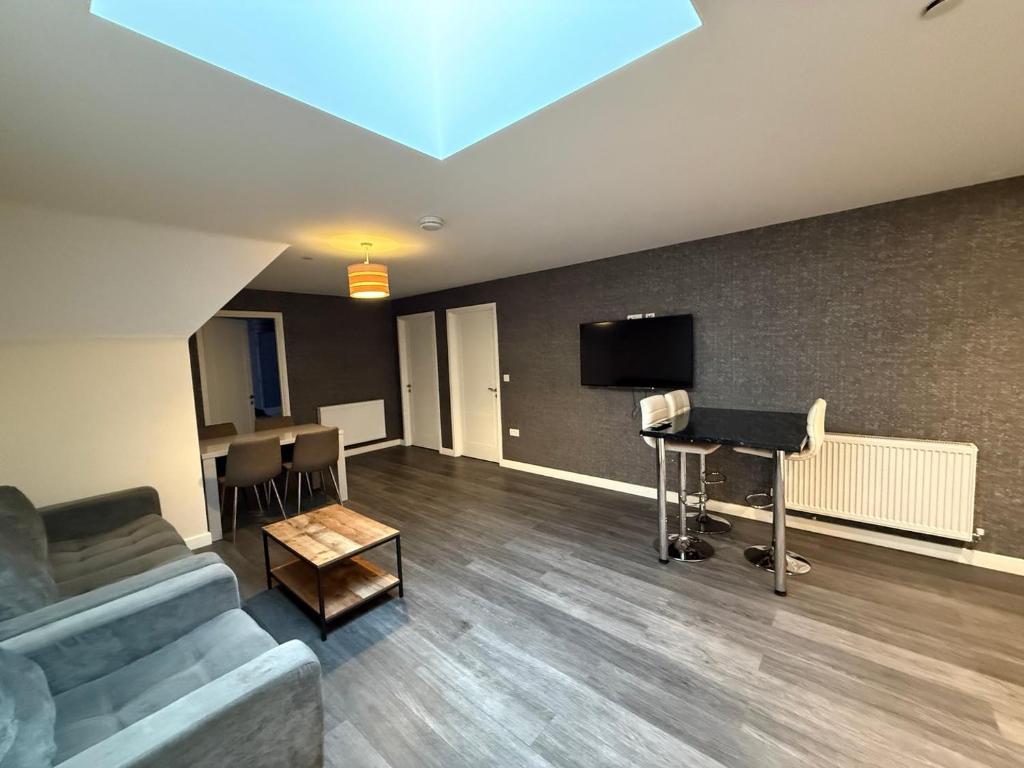 a living room with a couch and a desk and a television at Magna House in Egham