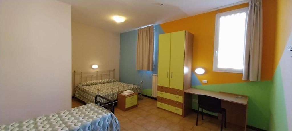 a room with two beds and a desk and a window at Casthello Ostello di Vallecamonica in Breno