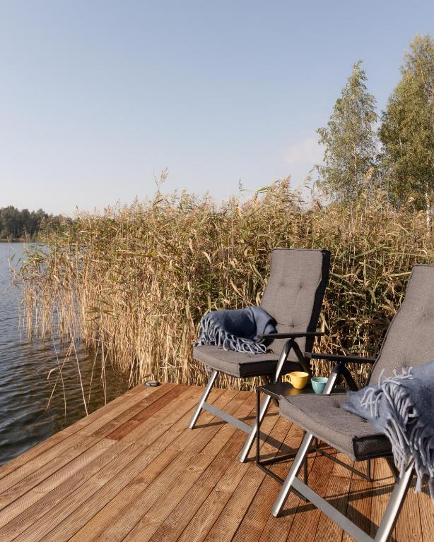 two chairs sitting on a dock next to the water at Laumiņas in Pavasari