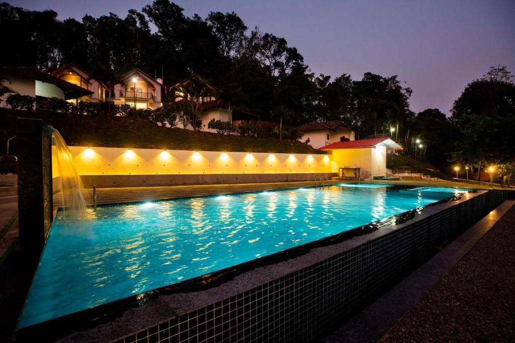 ein Schwimmbad bei Nacht mit Beleuchtung in der Unterkunft The Nest Bettathur, Coorg in Madikeri