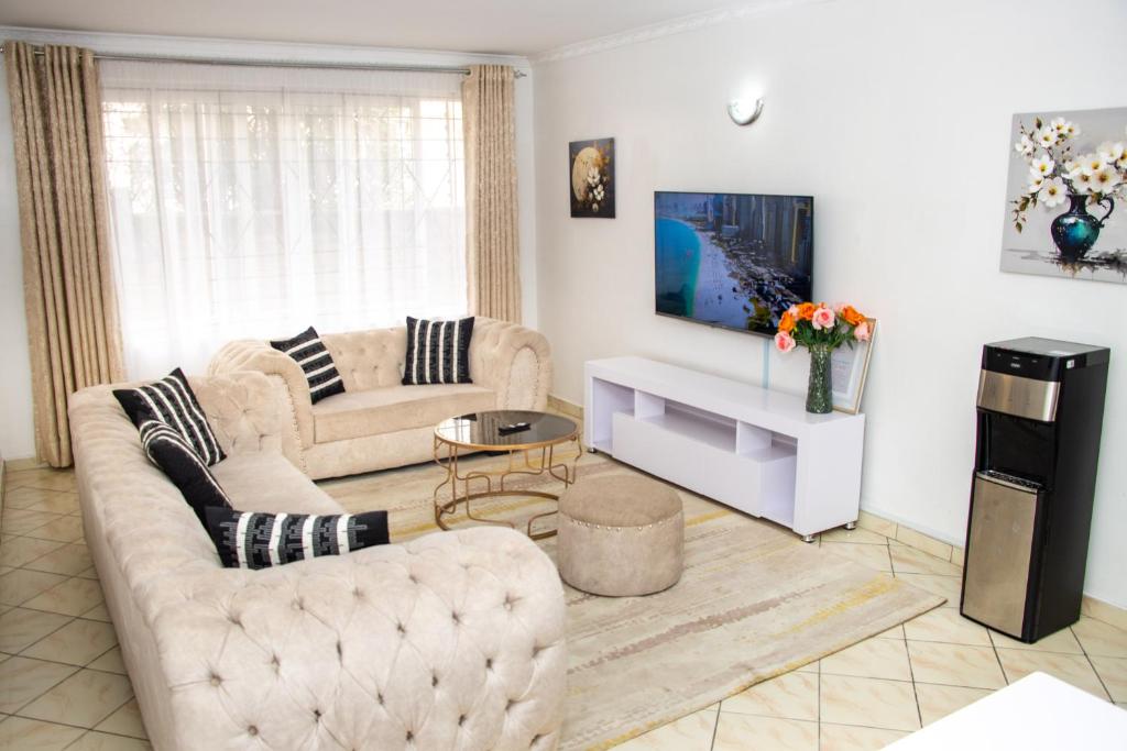 a living room with two couches and a tv at Cozy urban homes in Nakuru