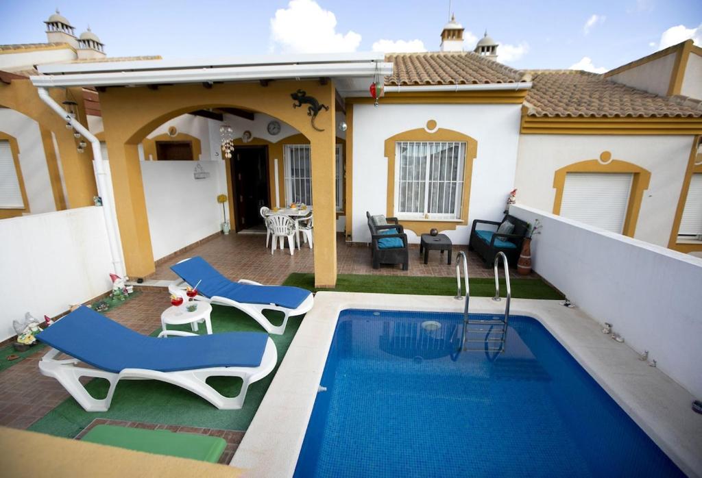 a backyard with a swimming pool and chairs and a house at Bluemoon 2 in Mazarrón