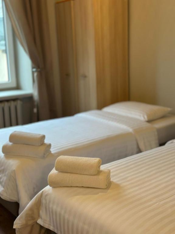 three beds in a room with folded towels on them at Hostel H360 - dawniej Hotelik Relax in Łódź