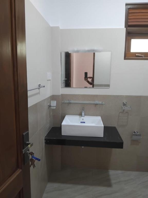 a bathroom with a white sink and a mirror at Hotel & Restaurant Chingari Pinnawala in Rambukkana
