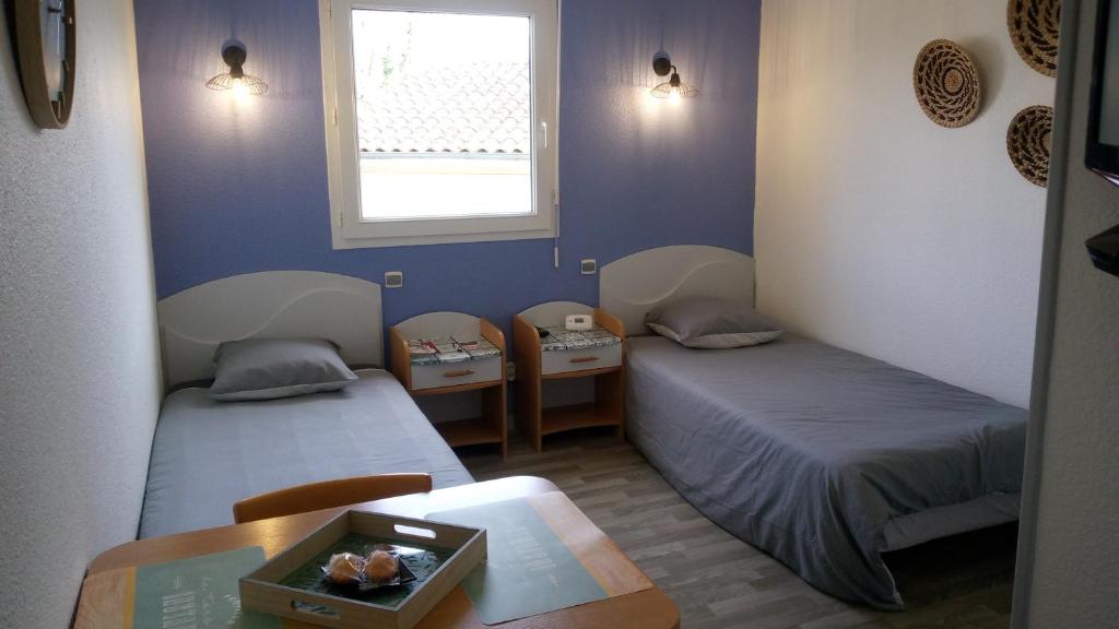 a room with two beds and a table and a window at Les Clés Nature Studio 41 in Moutiers-sous-Chantemerle