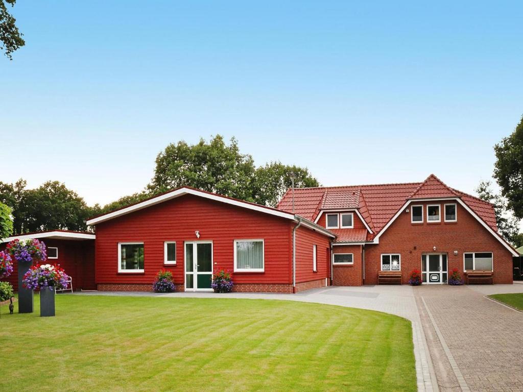 a red house with a green lawn in front of it at Ferienwohnung Landblick, Rastede in Rastede