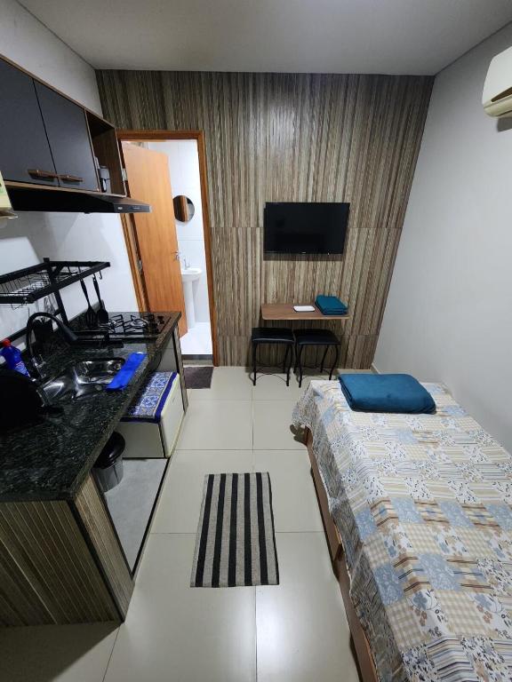 a small hotel room with a bed and a kitchen at Studio Aconchegante in Lins