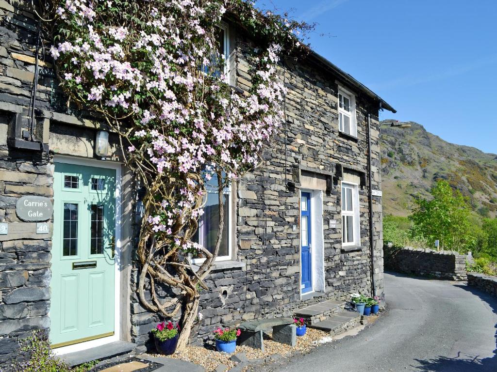 a stone house with a flowering tree in front of it at Carrie's Gate in Coniston