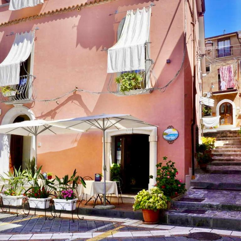 a pink building with tables and umbrellas in front of it at Donna Alda Affittacamere Capitello dal 2012 in Villammare