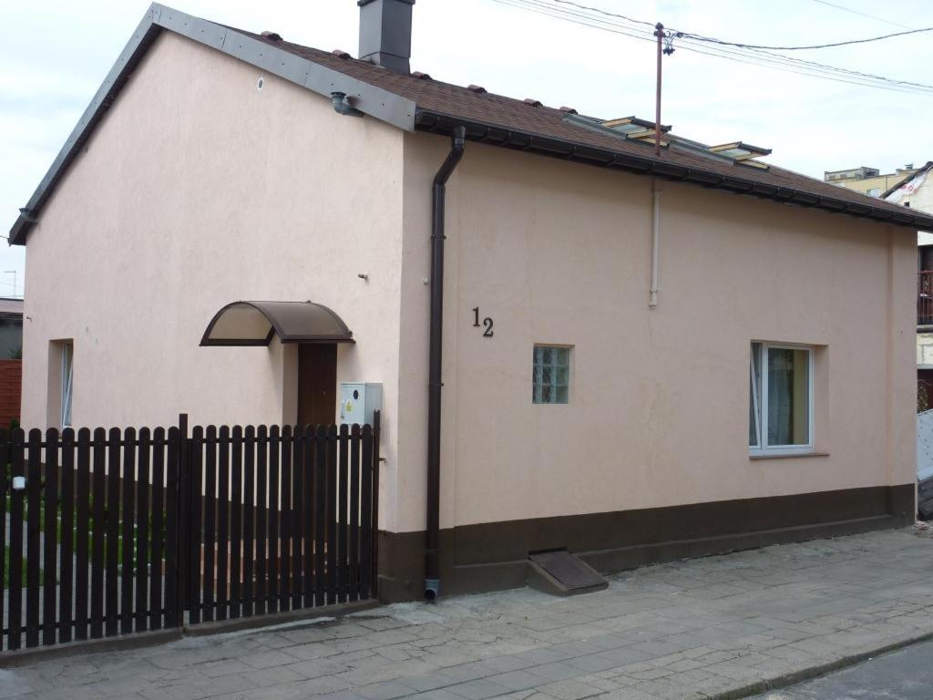 a small white house with a black fence at Noclegi Ściegiennego in Sosnowiec