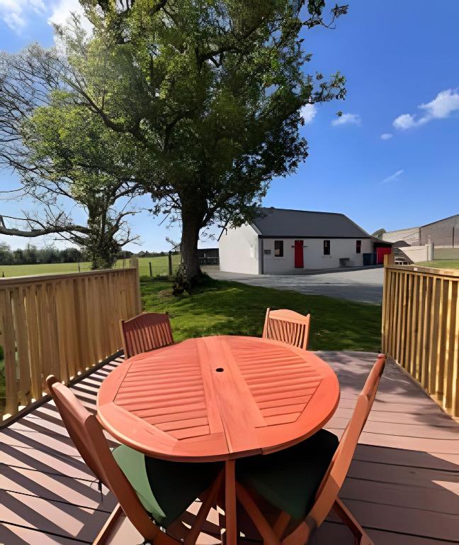 a wooden table and chairs on a deck with a tree at Historic Louisburgh Farm Cottage in Louisburgh