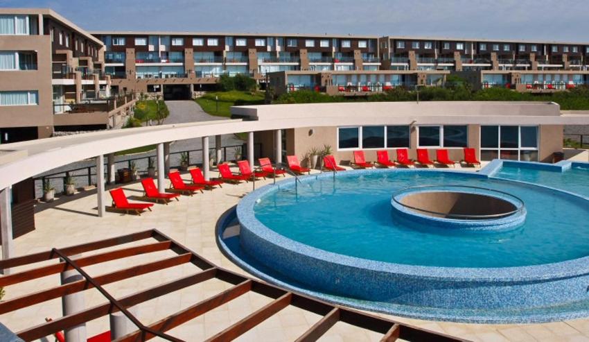 una gran piscina con sillas rojas y un edificio en Apartment in Linda Bay Complex en Mar de las Pampas