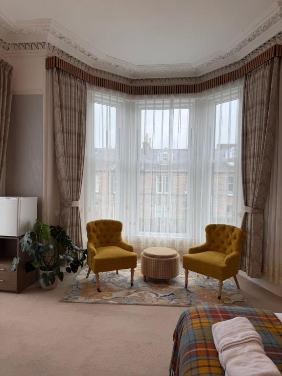 a bedroom with two chairs and a large window at Kingston Guesthouse in Edinburgh