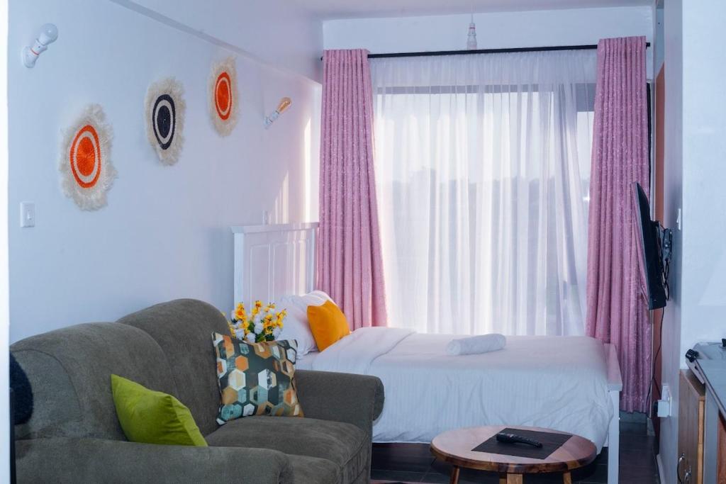 a bedroom with a bed and a couch and a chair at comfystdkiambu in Kiambu
