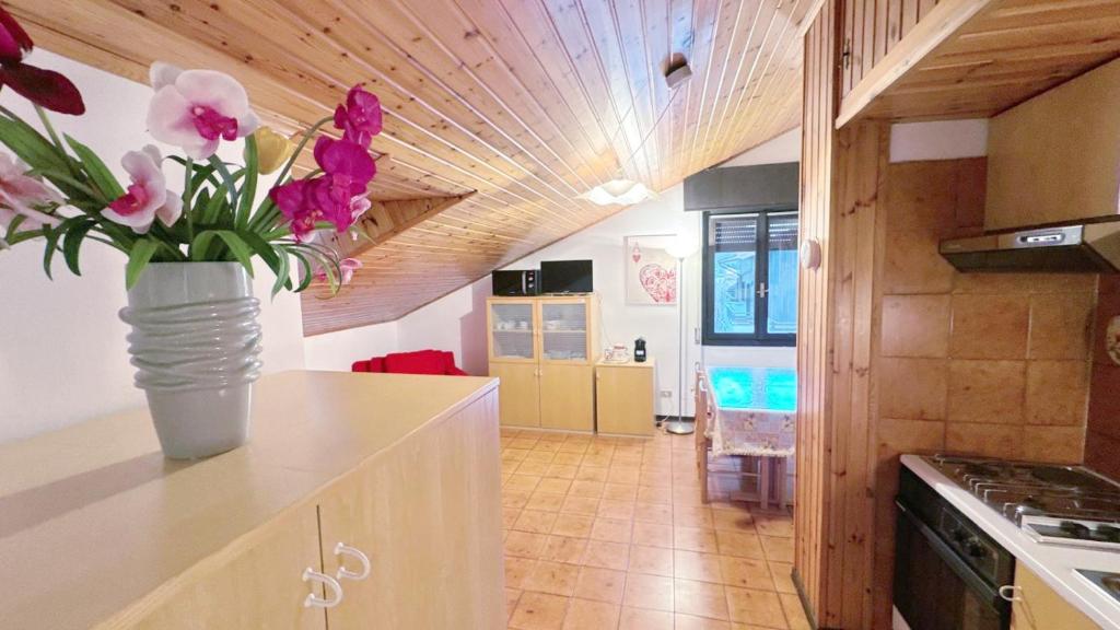 a vase of flowers on a counter in a kitchen at Baradello Apartment & Flat by ca-Sa Check in Le Bratte