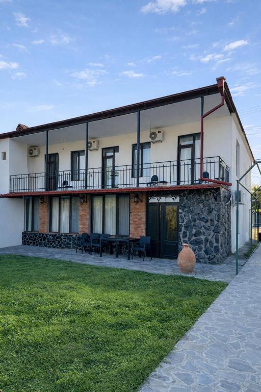 a building with a balcony and tables and chairs at Ortevani Guest House in Kvareli