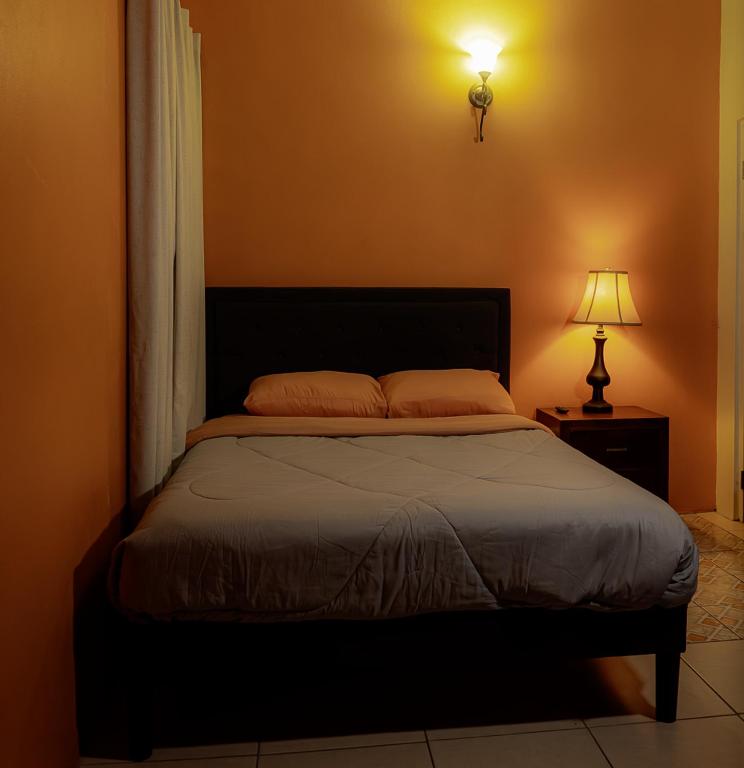 a bedroom with a large bed with a lamp and a bed sidx sidx sidx at Getaway Homes in Basseterre