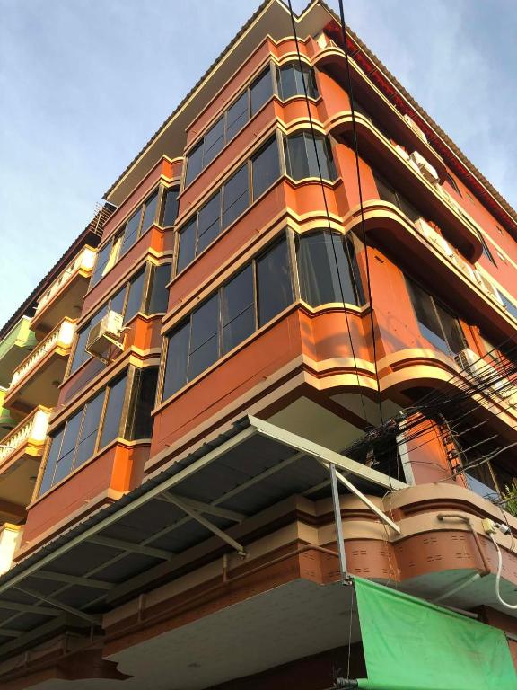 a tall orange building with a green flag in front of it at จอมเทียน ซีไซด์ เกสเฮ้าส์ in Jomtien Beach