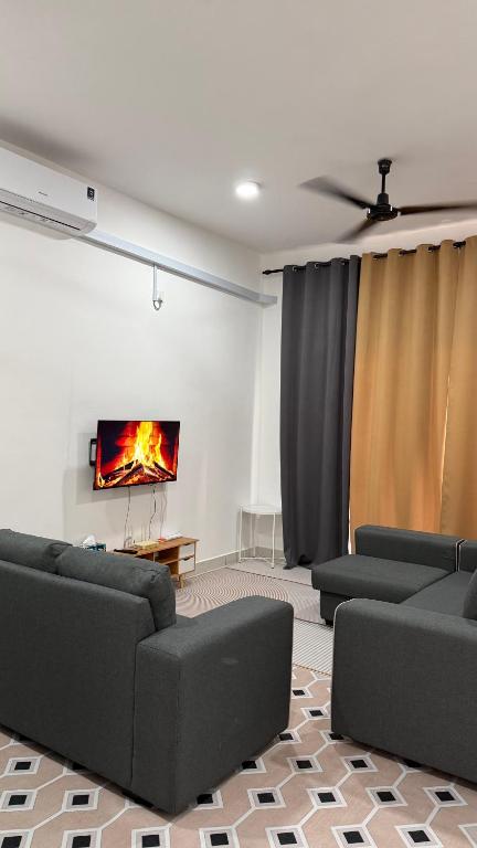 a living room with couches and a tv on a wall at Homestay Azizi in Seri Iskandar
