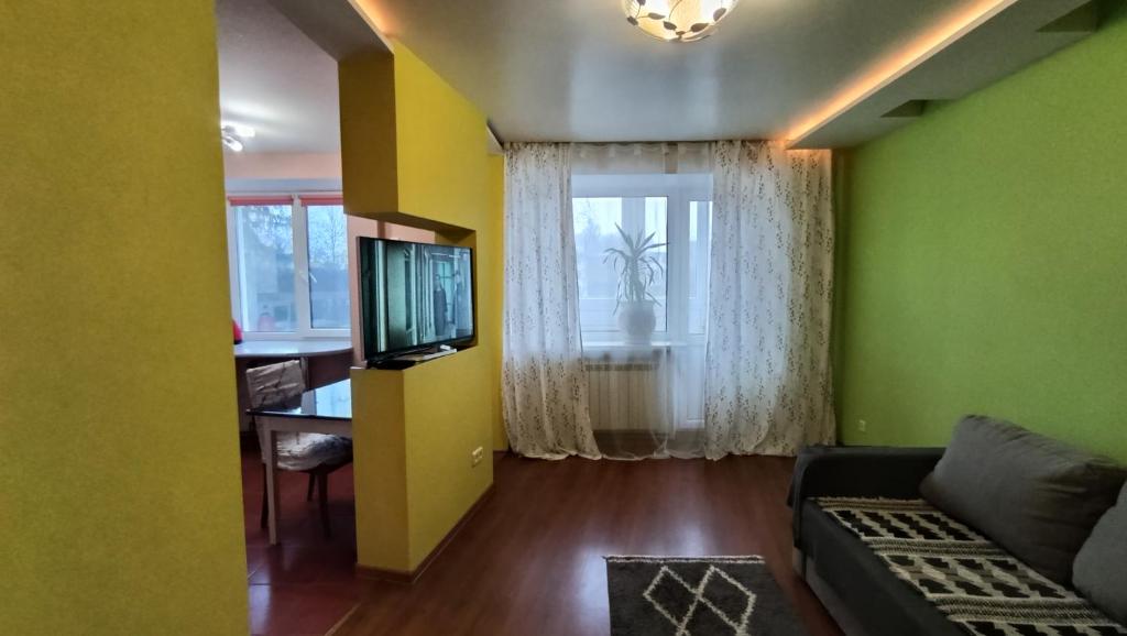 a living room with a couch and a tv and a window at Home for you in Ternopil
