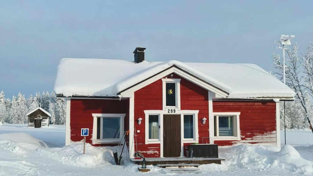 a small red house with snow on the roof at Einon Tupa in Kittilä