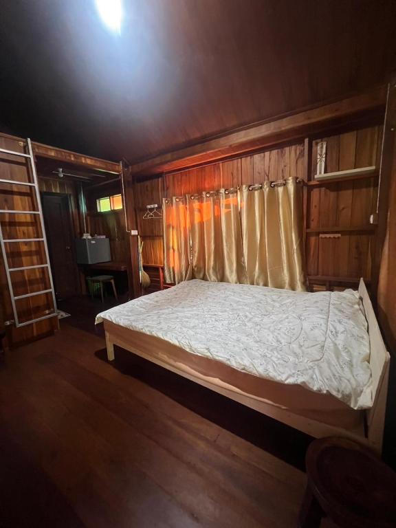 a bedroom with a bed in a wooden room at Namosototie in Ranong